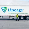 Man in high-vis jacket walking in front of a Lineage truck